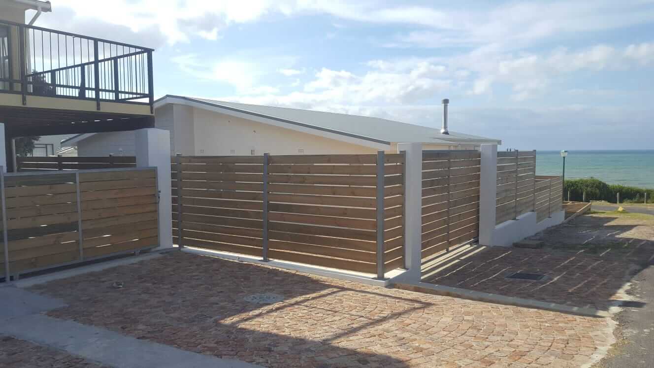 Horizontal slat fence and gate beside a house
