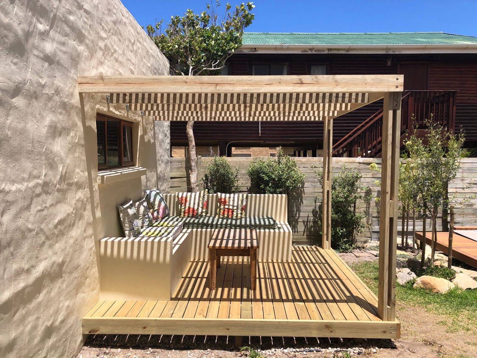 Pergola with built-in seating and striped shade cloth