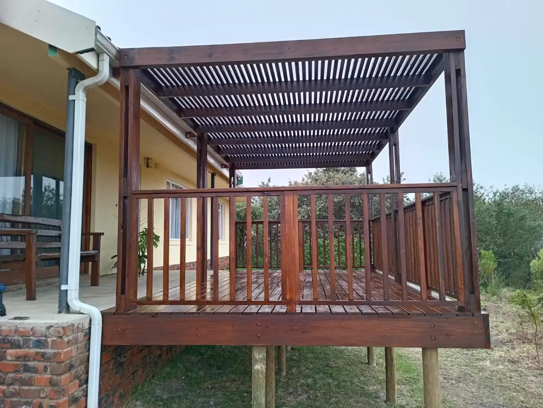 Raised deck with railing under a slatted pergola roof